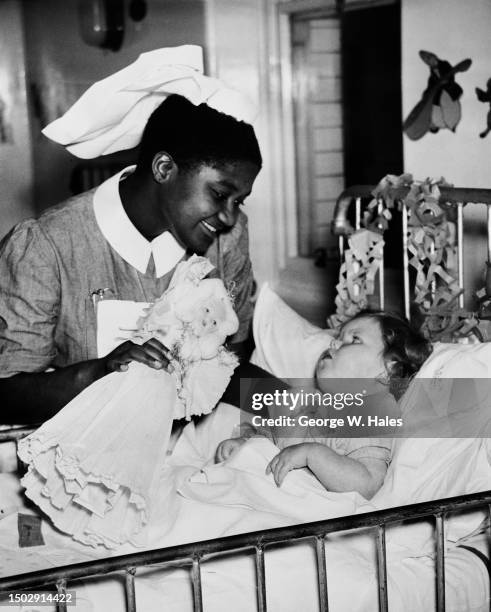 Ghanaian nurse Takyiaw Prempeh shows a doll to patient Linda McAndrew during the Christmas celebrations at Princess Alice Hospital in Eastbourne,...