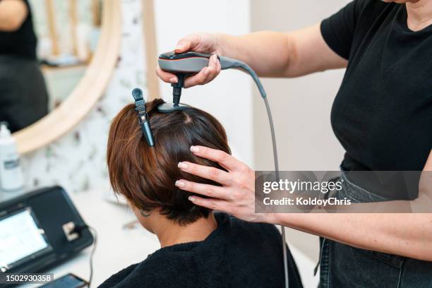 revitalizing hair: woman undergoing radiofrequency treatment for alopecia at hair clinic - hairline polished metal bildbanksfoton och bilder