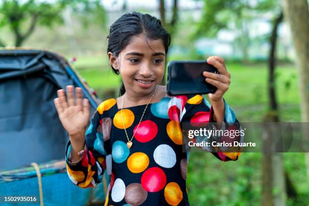 beautiful asian girl waving while making video call with her smartphone - dwarf girl stock pictures, royalty-free photos & images