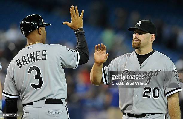 First Base Coach Harold Baines of the Chicago White Sox celebrates the teams win with teammate Kevin Youkilis during MLB game action against the...