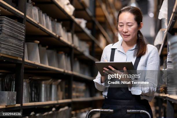 using an order management system is software that makes it easier to fulfill customer orders. a female shop owner uses a tablet computer inside the storehouse to order verify and match stock levels till delivery. - financial analyst stock pictures, royalty-free photos & images
