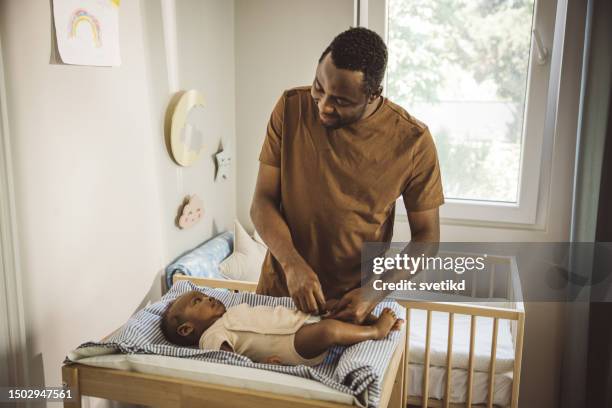 padre che cambia vestiti e pannolini al suo bambino a casa. - adult baby boy diaper change foto e immagini stock