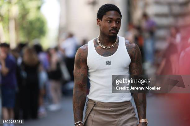 Fashion Show Guest is seen wearing a white loewe tank top with the black logo on the breast, jewelry and light brown leather trousers outside during...