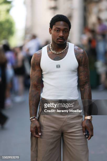 Fashion Show Guest is seen wearing a white loewe tank top with the black logo on the breast, jewelry and light brown leather trousers outside during...
