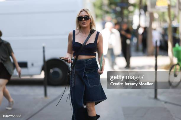 Fashion Show Guest is seen wearing black shades, a dark blue bra, a jeans skirt which has diffferent lenths for both legs, a black bag and black...