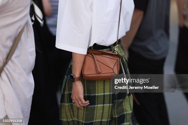 Fashion Show Guest is seen wearing a caro green denim skirt, a white shirt and a brown loewe mini puzzle bag outside during the Loewe Menswear...