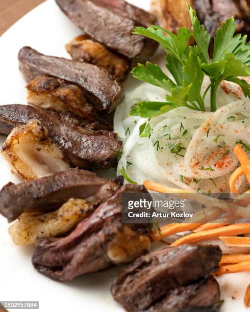 liver skewers with carrots and onions on a white plate. pieces of fried liver with bacon and vegetables are decorated with parsley. middle eastern cuisine. wooden background. top view. copy space - beef liver stock pictures, royalty-free photos & images