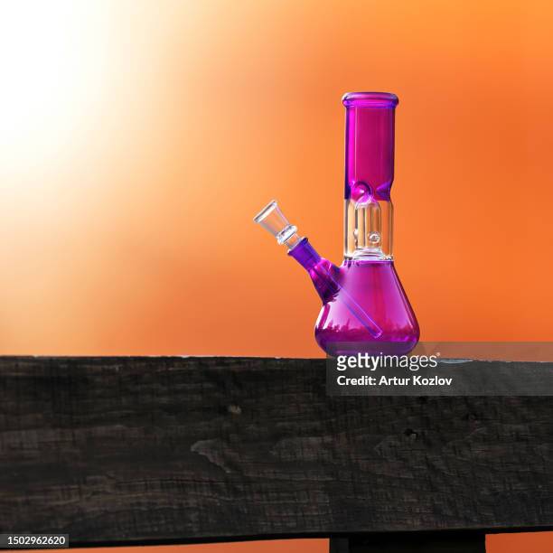 purple water bong for smoking marijuana on an orange background - smoking weed stock-fotos und bilder