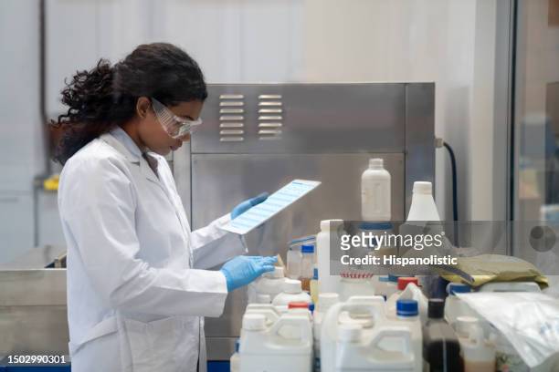 químico investigando mientras trabaja en un laboratorio industrial - hazmat fotografías e imágenes de stock