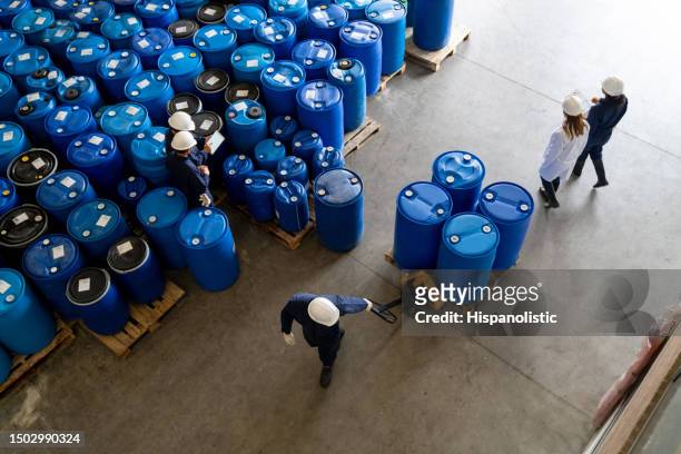 mitarbeiter, die in einer chemiefabrik arbeiten, bewegen fässer mit substanzen - ölfass stock-fotos und bilder