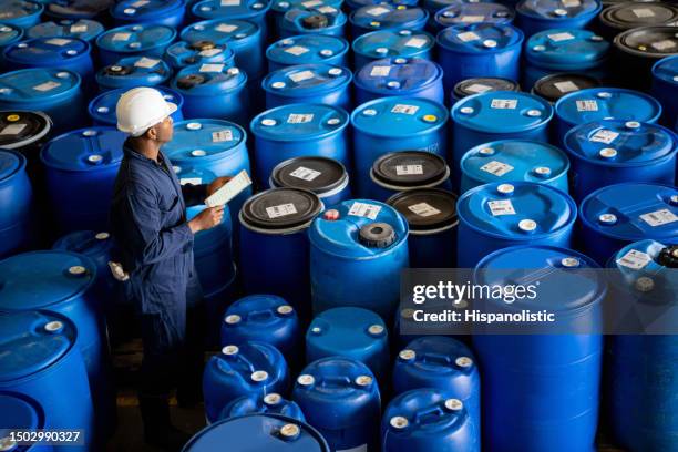 chemical plant worker doing a stock inventory of barrels at a distribution warehouse - hazardous substances stock pictures, royalty-free photos & images