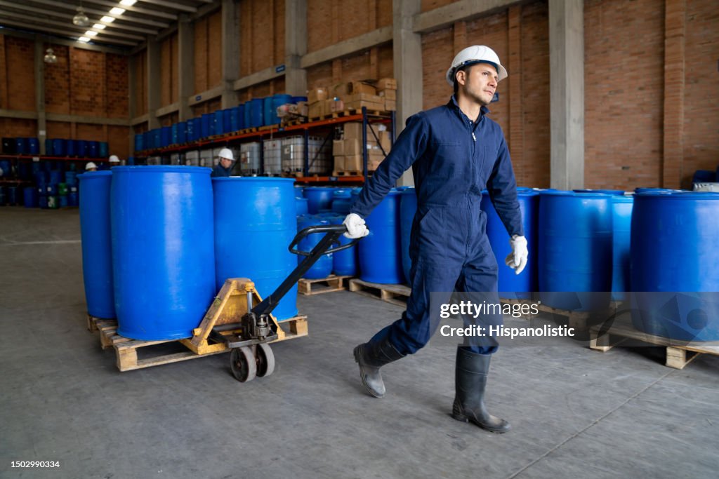 Chemical plant worker moving barrels using a forklift