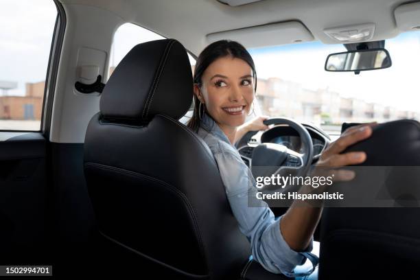 woman driving a car and looking back to reverse - reversing stock pictures, royalty-free photos & images
