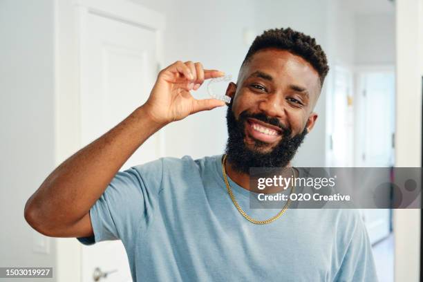 young man holding invisible dental aligners - aparelho dentário imagens e fotografias de stock