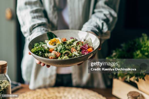 woman mixing delicious superfood salad ingredients with wooden spoons in kitchen - salad tossing stock pictures, royalty-free photos & images