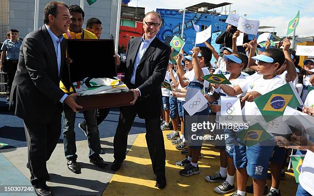 Rio de Janeiro state governor Sergio Cabral and Brazilian Olympic Committee president Carlos Arthur Nuzman show the Olympic flag to children and...
