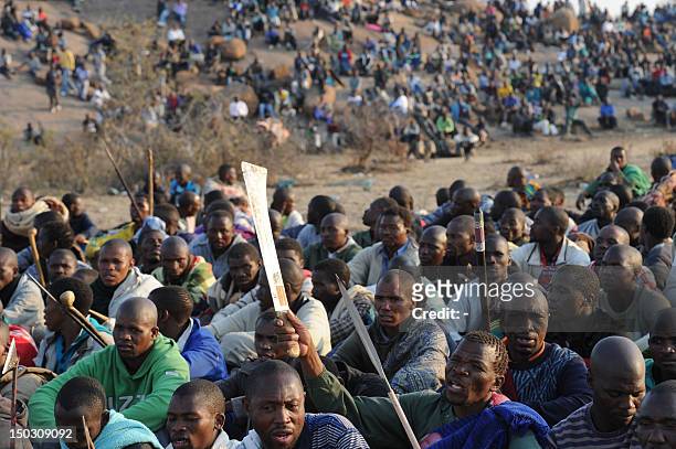 Striking mineworkers armed with machetes are monitered by a large number of police as they stage a sit-in on a hill near the mine in Rustenburg, 100...