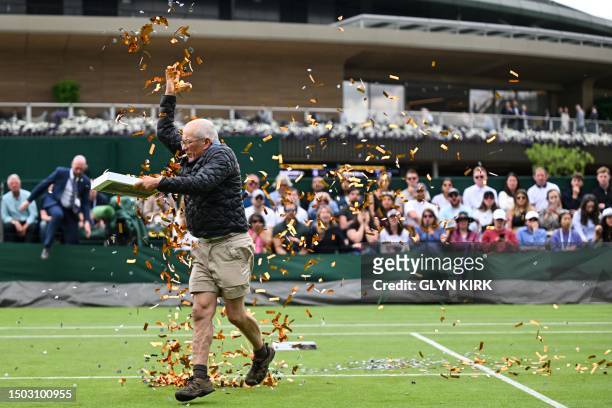 Just Stop Oil demonstrator throws orange confetti on court 18 as he disrupts the women's singles tennis match between Australia's Daria Saville and...