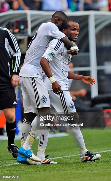 Gershon Koffie of the Vancouver Whitecaps hugs teammate Dane Richards, after Richards scored in the second half of the game against Real Salt Lake at...