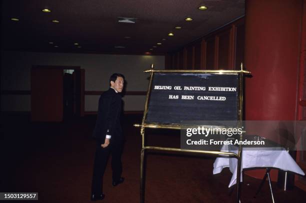 An unidentified man stands beside a sign in the Great Wall Sheraton hotel, which had been closed by police during ongoing pro-democracy...