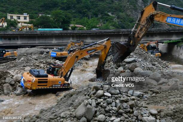 Excavators work to clear mud and debris from the road at a landslide site on June 27, 2023 in Wenchuan County, Sichuan Province of China. Seven...