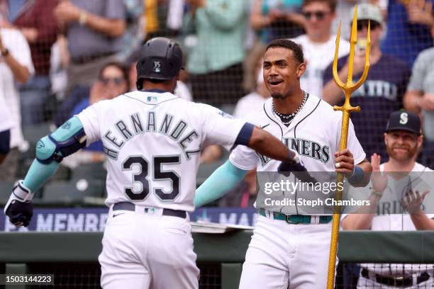 Teoscar Hernandez of the Seattle Mariners reacts after his two-run home run with Julio Rodriguez and the team's trident during the first inning...