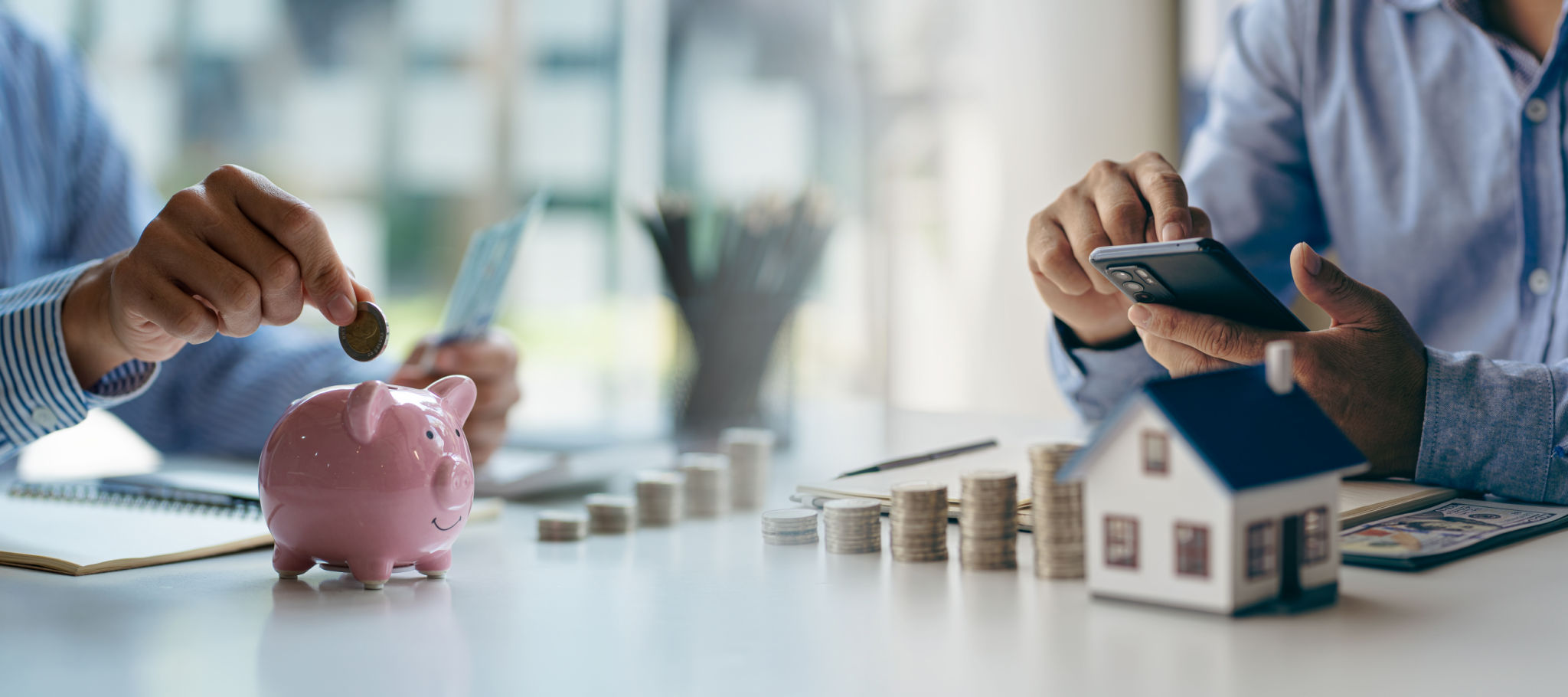 Coins in piggy bank with wooden house on table to save money for house purchase, financial concept for savings and borrowing. Horizontal cross section. Coins in piggy bank with wooden house on table to save money for house purchase, financial concept for savings and borrowing. Horizontal cross section.