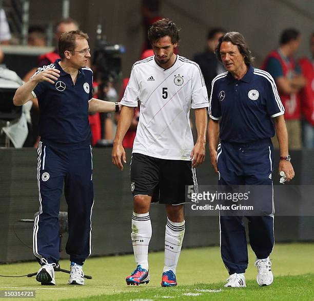 Mats Hummels of Germany is led off the pitch by team doctors Tim Meyer and Hans-Wilhelm Mueller-Wohlfahrt during the international friendly match...