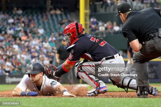 Jarred Kelenic of the Seattle Mariners scores a run at home plate against Keibert Ruiz of the Washington Nationals during the seventh inning at...
