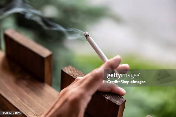a woman is holding a smoking cigarette in her hand, with which she smokes. - stop smoking stock pictures, royalty-free photos & images
