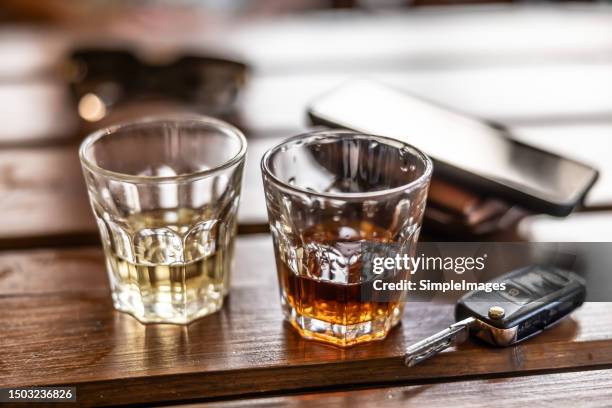 two glasses of hard alcohol and car keys on a table in a pub. the irresponsibility of driving car and drinking alcohol. - hard liquor stock pictures, royalty-free photos & images