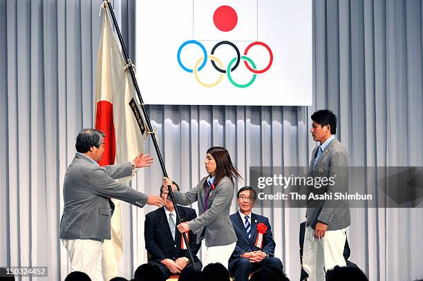 Wrestling gold medalist Saori Yoshida returns the Japanese flag to Chef de Mission Haruki Uemura during the disbandment ceremony on August 14, 2012...