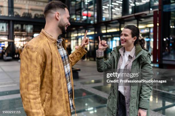 deaf couple connects through sign language on evening promenade - woman fingers in ears stock pictures, royalty-free photos & images