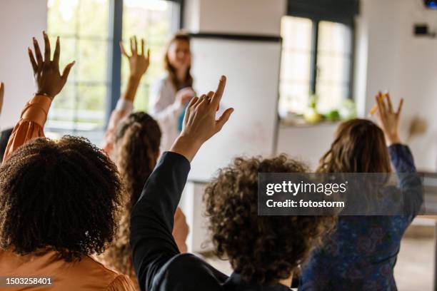 businesswoman writing on whiteboard while holding a presentation for a group of business people - vragen en antwoorden stockfoto's en -beelden