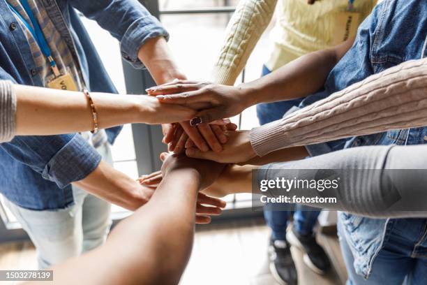 close up shot of diverse hands stacked together in unity - humanitaire hulp stockfoto's en -beelden