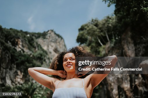 A confident young woman looks joyful and satisfied to be on a beautiful beach, enjoying a well deserved holiday A confident young woman looks joyful and satisfied to be on a beautiful beach, enjoying a well deserved holiday
