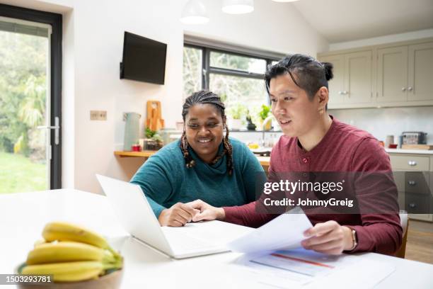 multiracial couple working on their budget at dining table - realism stock pictures, royalty-free photos & images
