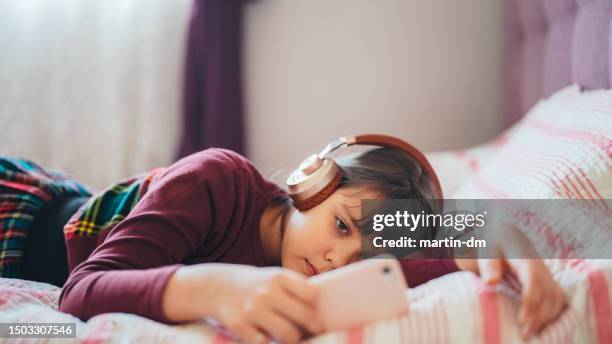 kind im bett schaut sich virale videos auf dem smartphone an - digital native stock-fotos und bilder