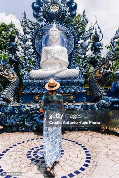 woman in blue dress and hat walking towards the white buddha at the blue temple in chang rai. - chiang rai province stock pictures, royalty-free photos & images