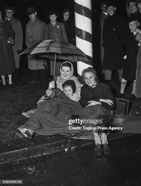 Mrs Goble with her five year-old son, Roy, and eleven year-old daughter, Joy, on the Mall in London the night before the return of Queen Elizabeth...