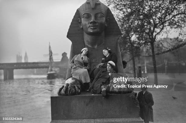 Three women apparently asleep on one of the Egyptian-style bronze sphinx statues on the Victoria Embankment in Westminster, London, 6th May 1935....