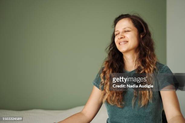 woman sitting cross legged on a bed with closed eyes - osminkad bildbanksfoton och bilder