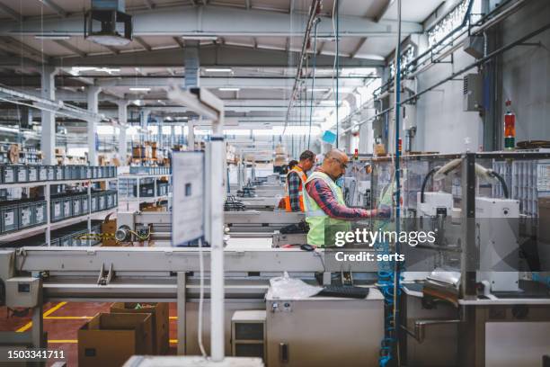 industriemitarbeiter arbeiten an der produktionslinie in der fabrik - fließbandfertigung stock-fotos und bilder