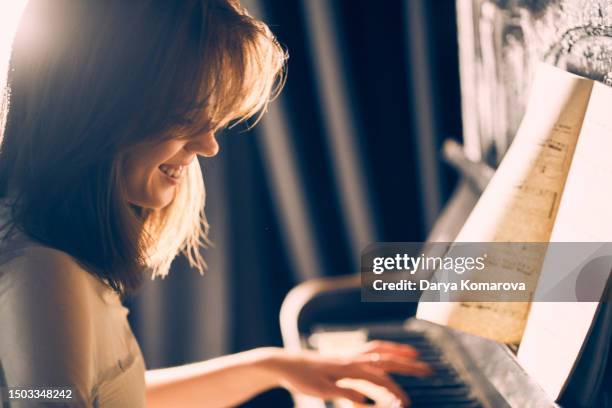 happy smiling woman playing the piano. the concept of favourite hobby, learning how to play music on keyboard instruments, the poster with copy space. - same person different looks stock pictures, royalty-free photos & images