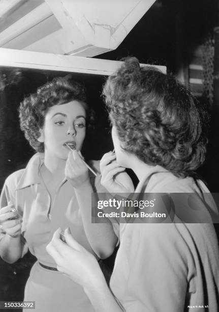 Actress Elizabeth Taylor touches up her lipstick, circa 1950.