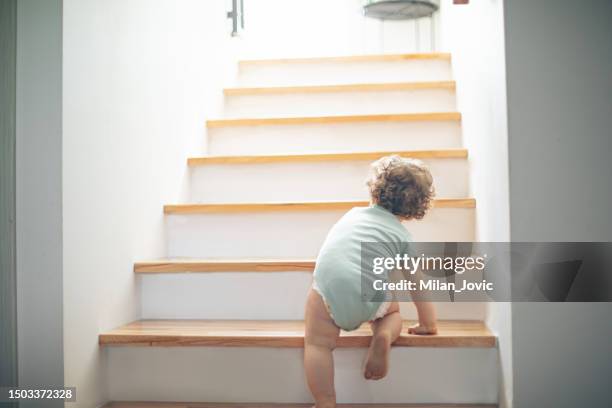 little cute toddler girl climbing on stairs at home - girl rising stock pictures, royalty-free photos & images