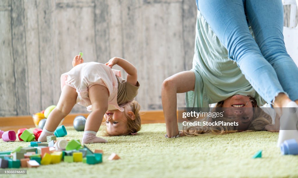Mother and daughter standing upside down on the carpet at home