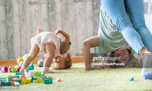 mother and daughter standing upside down on the carpet at home - flickbaby bildbanksfoton och bilder