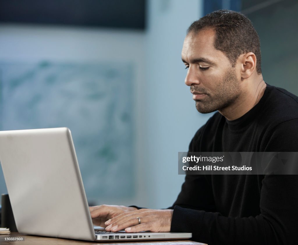 Mixed race man typing on laptop