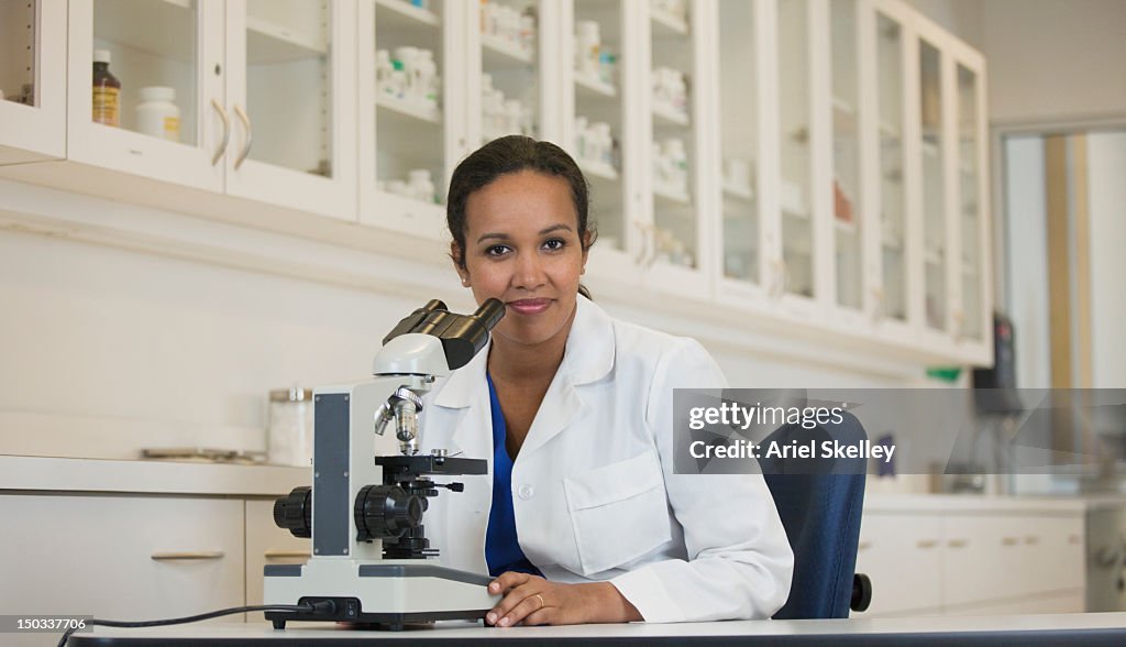 Gemischtes Wissenschaftler mit Mikroskop in einem Labor